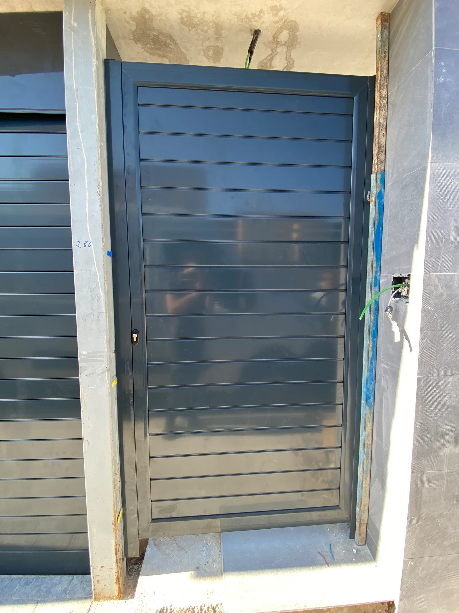Puerta de paso abatible en aluminio antracita instalada